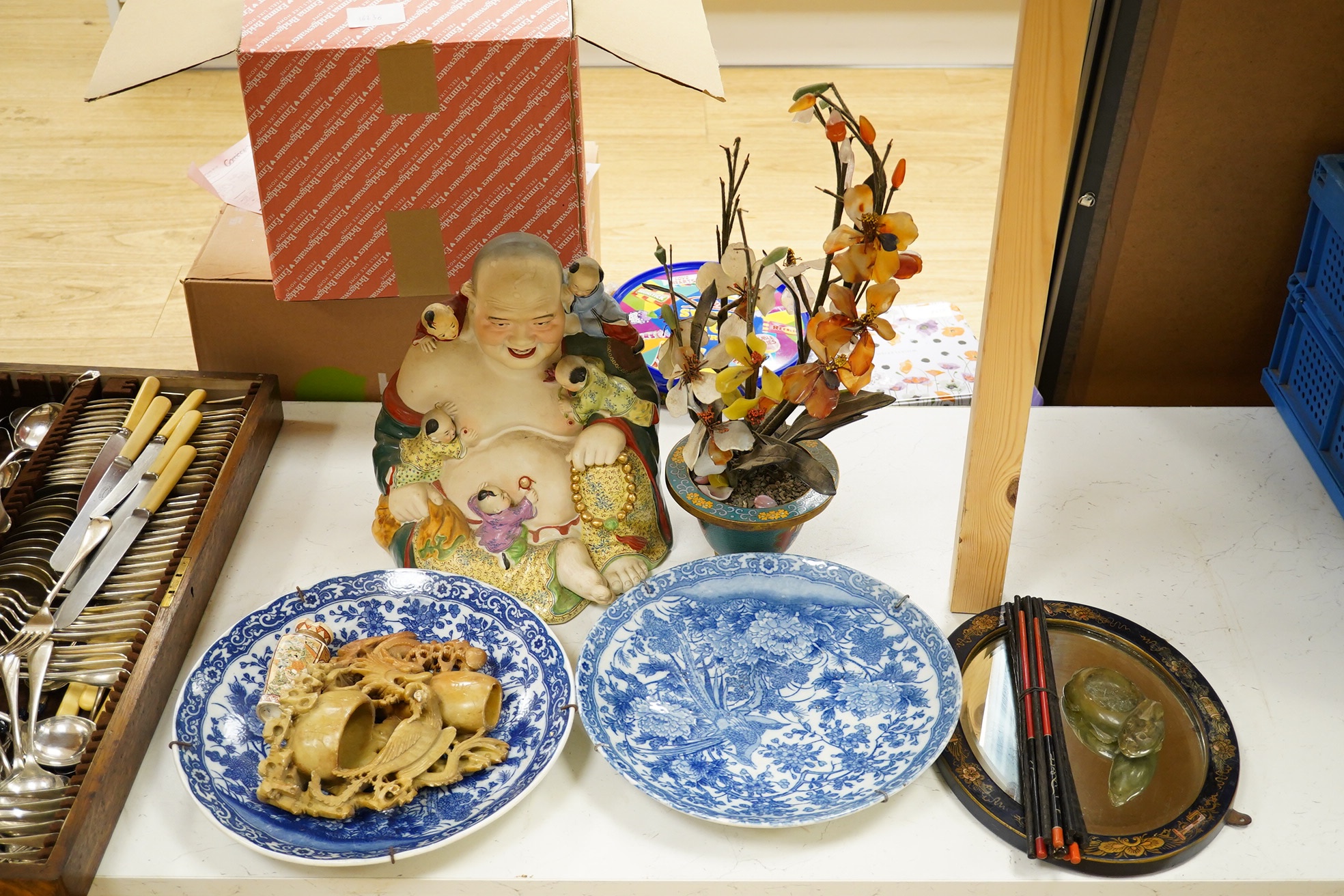 A collection of mostly Japanese and Chinese items including a floral hardstone flower in cloisonné pot, a hardstone carving of a Chinese Buddha and blue and white dishes. Condition - varies, fair